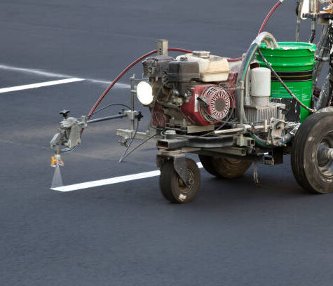 Construction worker using line painting machine on new parking lot.
