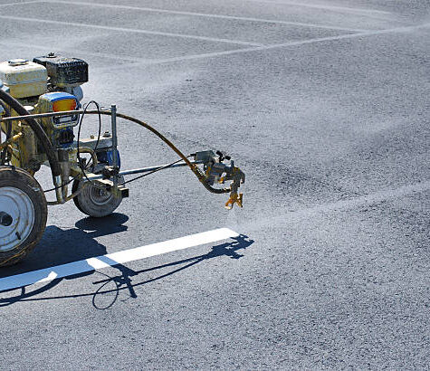 Striping machine painting lines onto fresh asphalt.