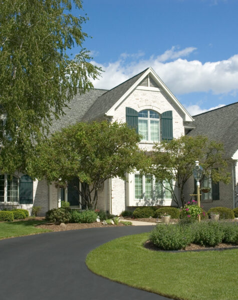 Beautiful white two story brick home. Very colorful photo with blue sky and green grass. Typical new home in the suburbs of the United States. Just one of many home or house photos in my gallery.